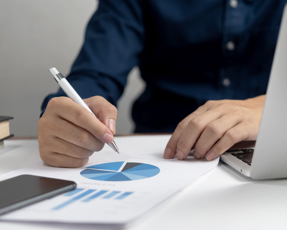 Man writing with a pen on a graph on a piece of paper