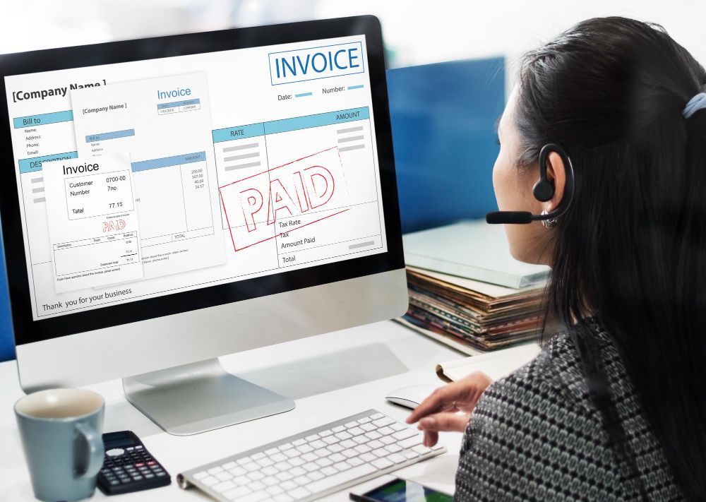 A woman is sitting in front of a computer with a headset on.