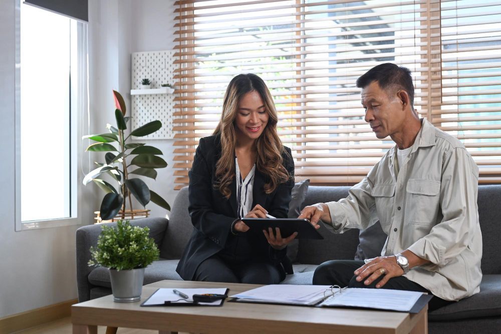 A man and a woman are sitting on a couch looking at a tablet.