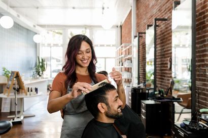 A woman is cutting a man 's hair in a salon.