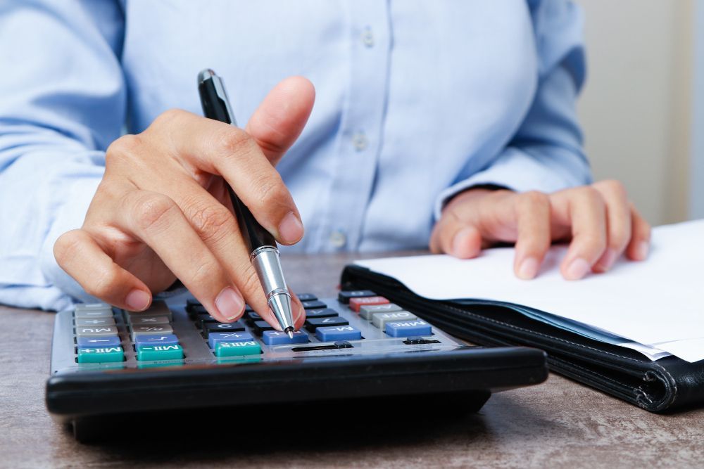 A person is using a calculator and writing on a piece of paper.