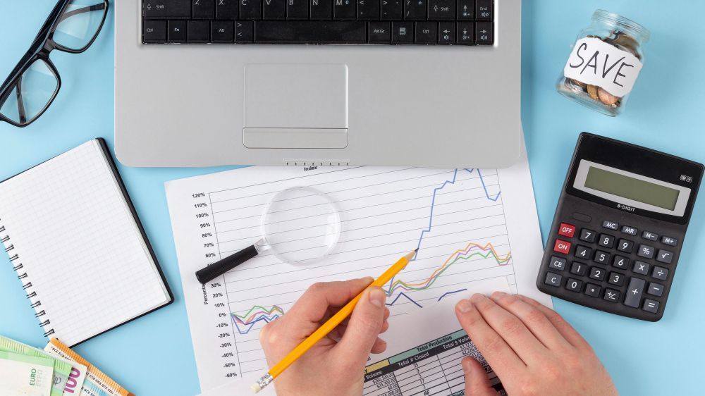 A person is using a magnifying glass to look at a graph on a piece of paper.