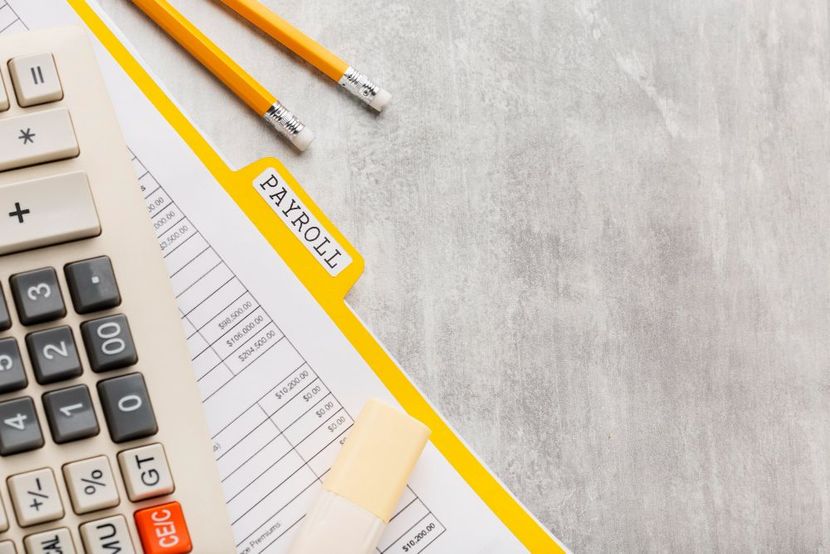 A calculator , pencils , and a payroll form are on a table.