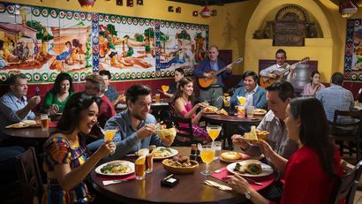 A group of people are sitting at tables in a restaurant eating and drinking.