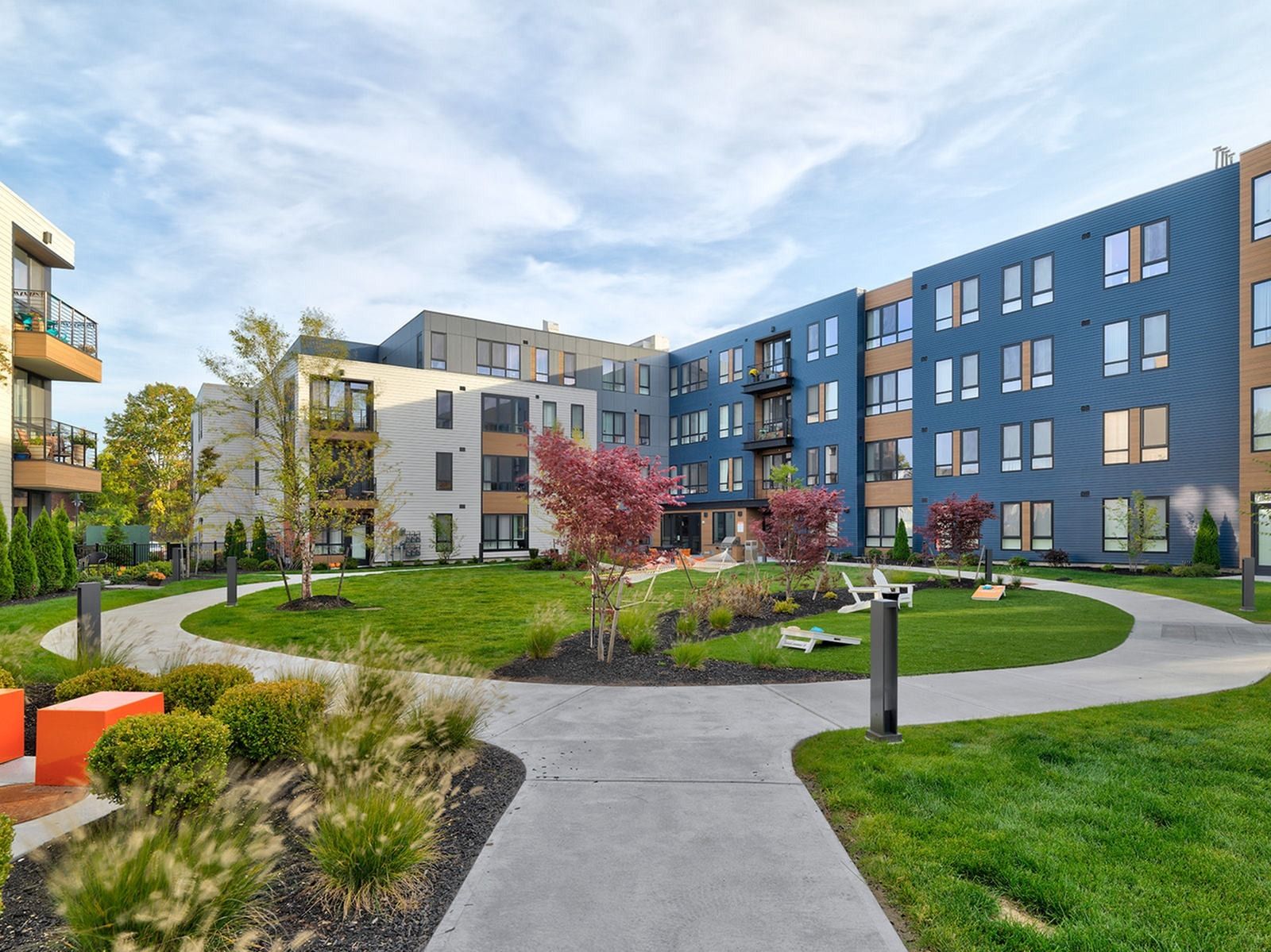 Exterior view of West End Yards' apartment community with green lawn and apartment building.