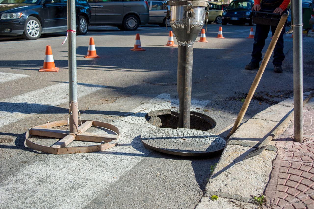 A manhole cover is being installed on the side of the road.
