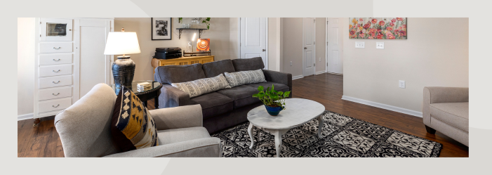 A living room with a couch , chair , coffee table and rug.