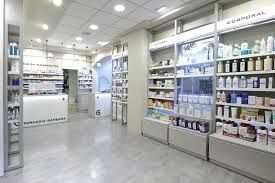 Interior de una farmacia bien iluminada con estantes de productos y un mostrador blanco.