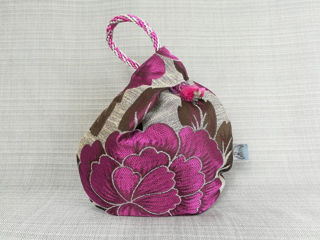 Handmade bags by Damson Moon Handmade cerise floral patterned knot bag with hand braided handle by Damson Moon