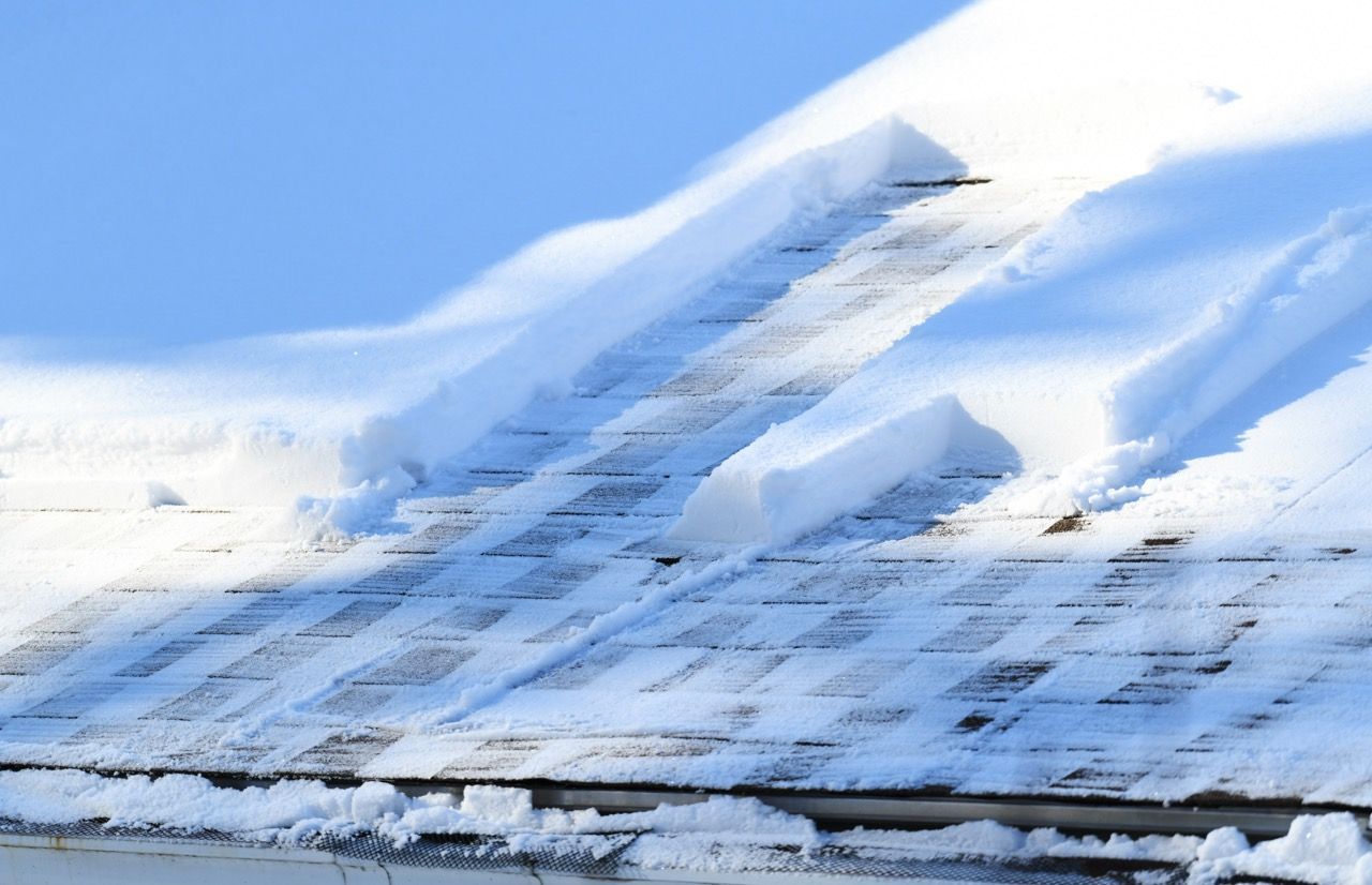Toit couvert de neige avec des sections de neige fondante et de ciel bleu visibles.