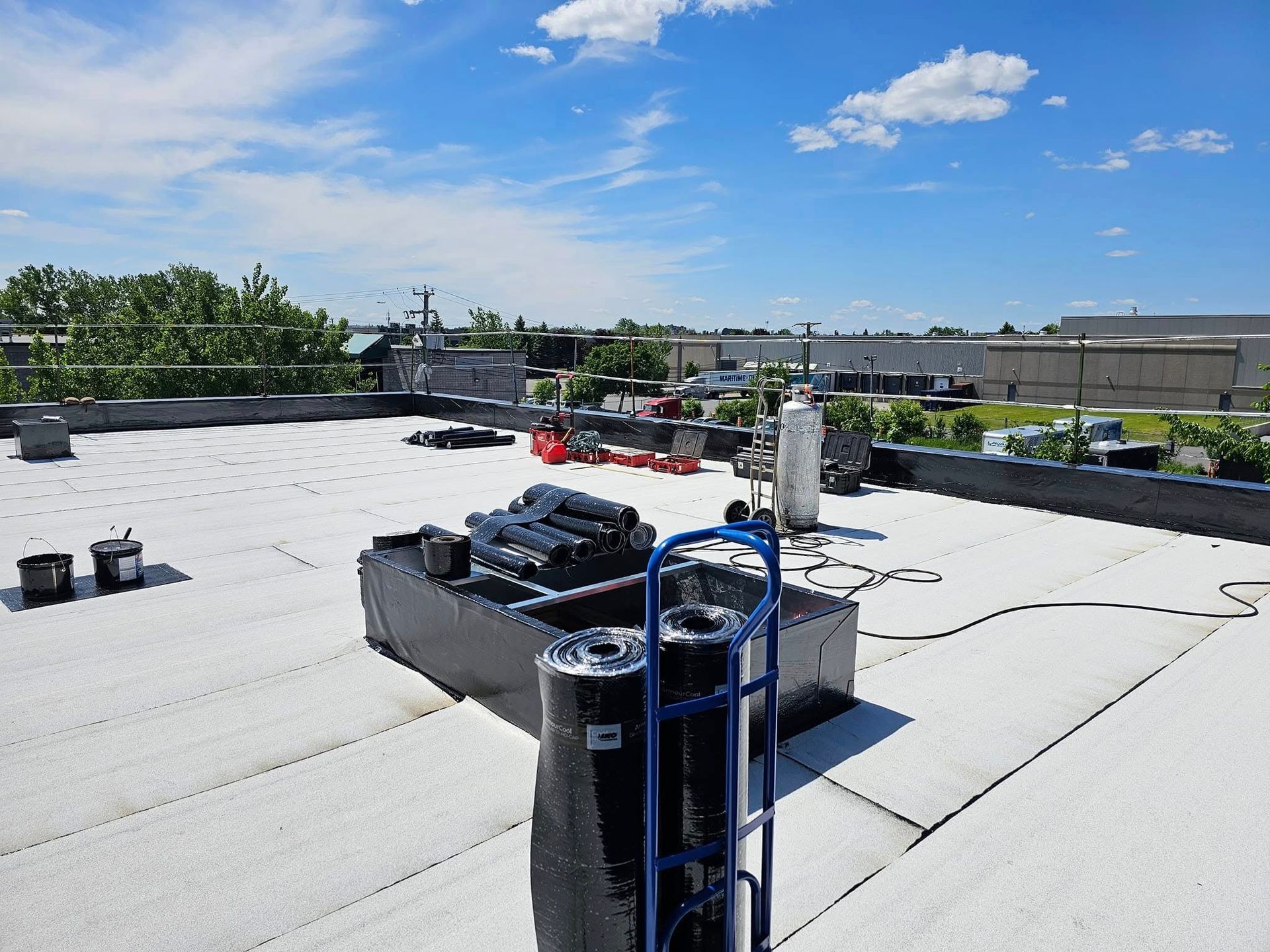 Toit avec matériaux de toiture et équipements sous un ciel bleu.
