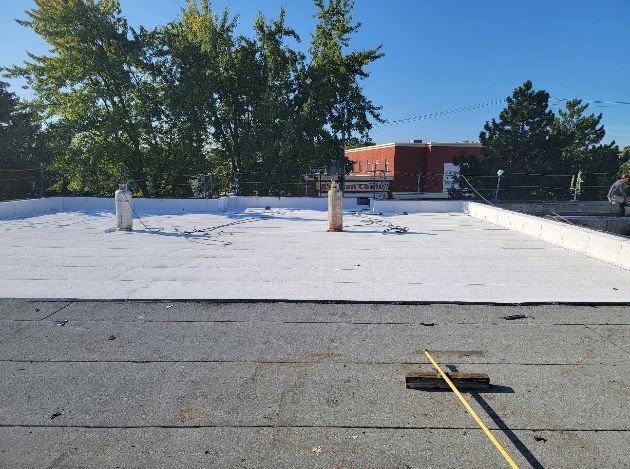 Toit commercial plat et blanc avec tuyaux d'aération, vu par une journée ensoleillée.