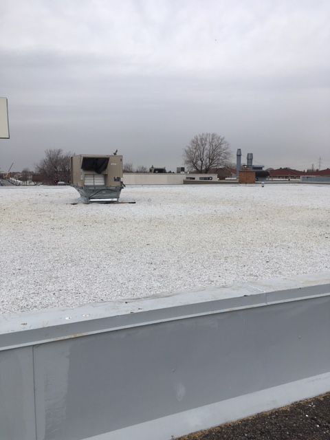 Un toit plat recouvert de gravier, un climatiseur et un ciel nuageux.