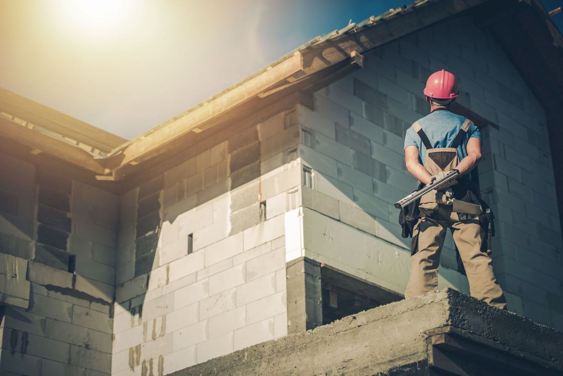 a man wearing a hard hat stands in front of a building under construction