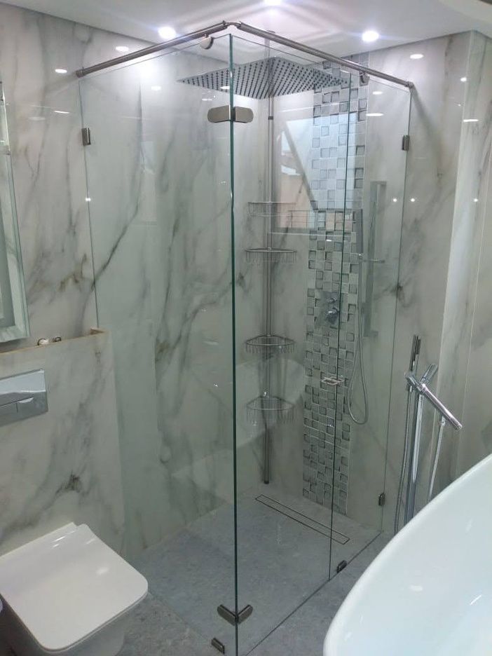 Cabinas de baño blancas en un baño público. Suelo oscuro, paredes blancas y negras, iluminación cenital.