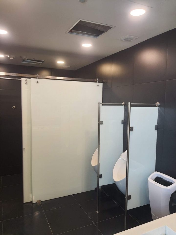 Cabina de ducha de cristal en un baño moderno con paredes de mármol e inodoro blanco.