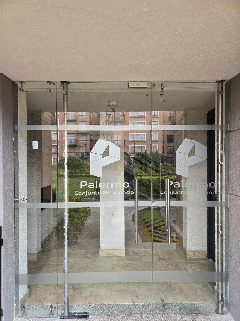 Edificio de ladrillo con balcones y ventanas de cristal. Cielo gris, cables de electricidad.