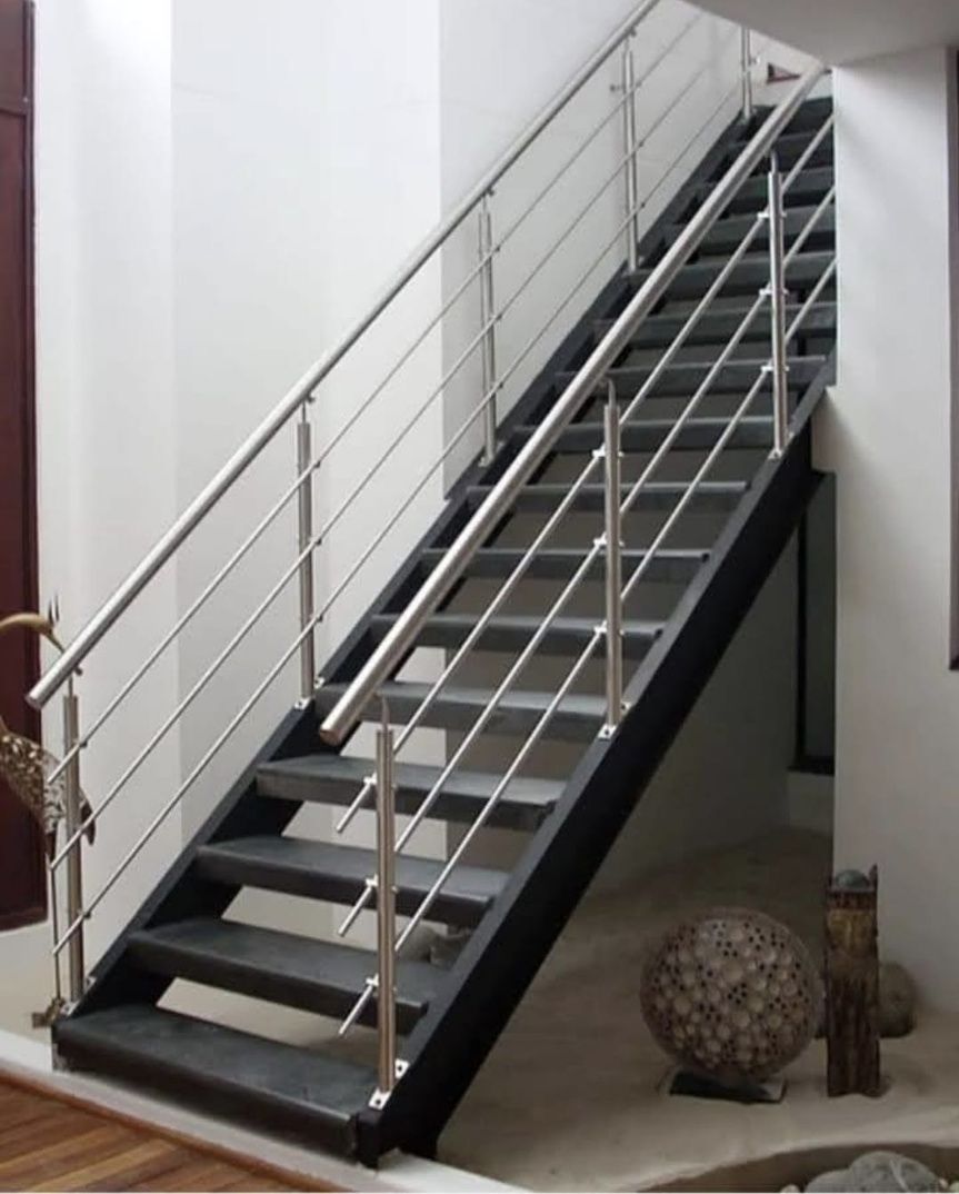 Escalera con barandillas de cristal y metal, suelos de madera noble y escalones descendentes.