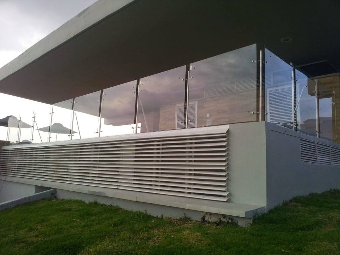 Vista desde la azotea de una ciudad bajo un cielo nublado. Patio de hormigón gris con una barrera de cristal.