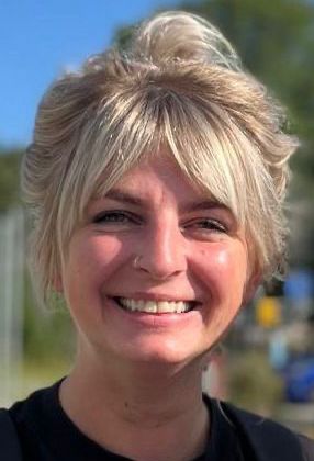 Eine Frau mit kurzen blonden Haaren lächelt in die Kamera.
