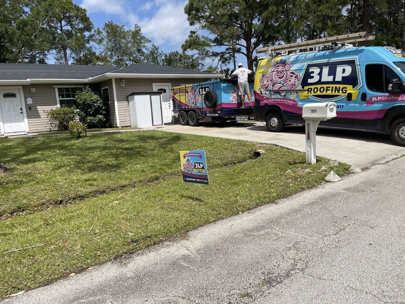 A 3LP Roofing van and trailer parked at a house, with a worker on the trailer and a company sign on the lawn.