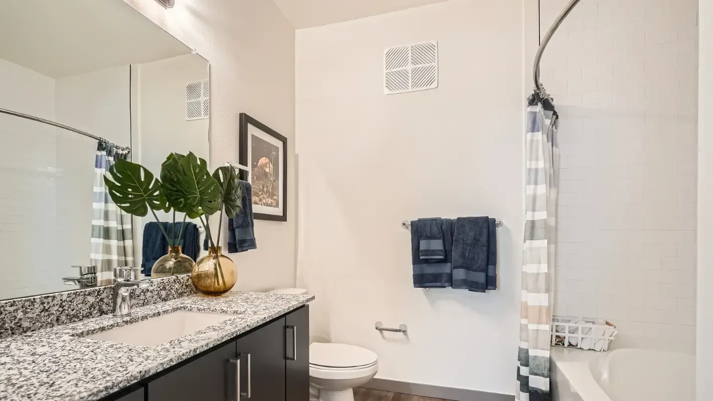 Bathroom in an apartment with granite vanity, double sink, toilet, and tub/shower.