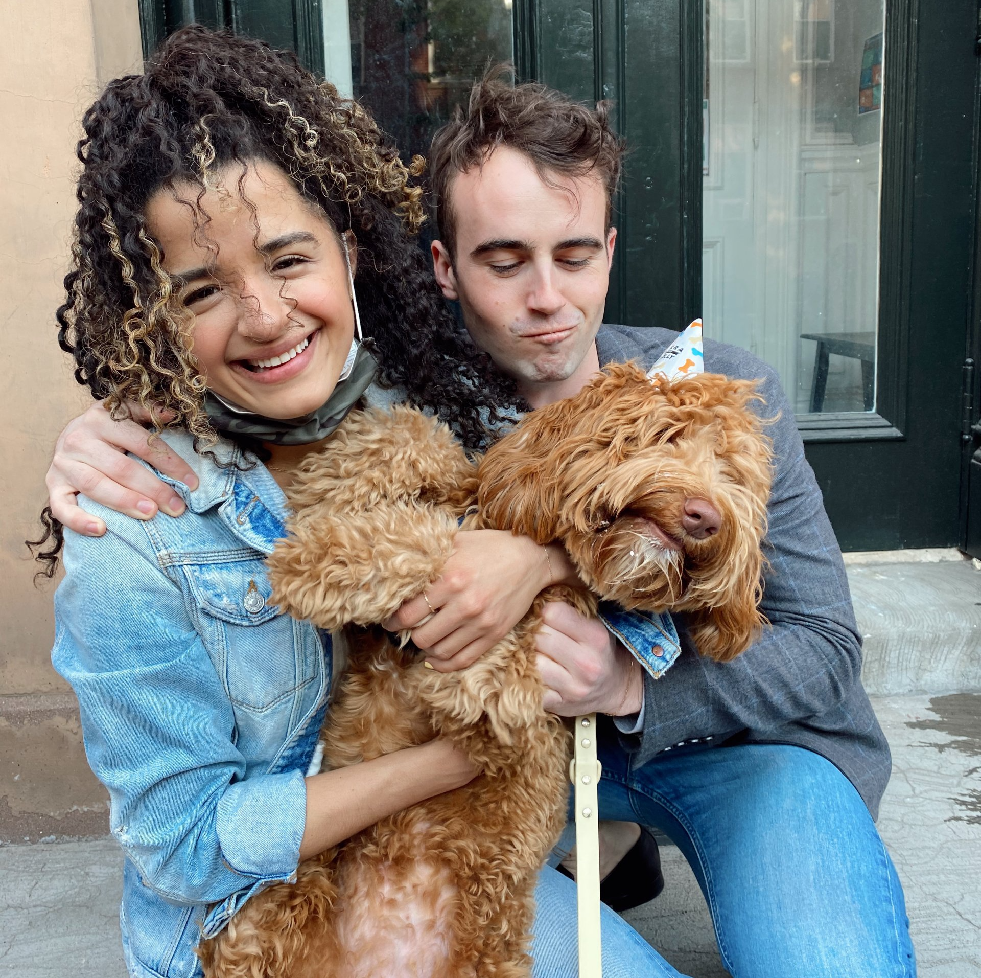 A man and woman are holding a brown dog on a leash