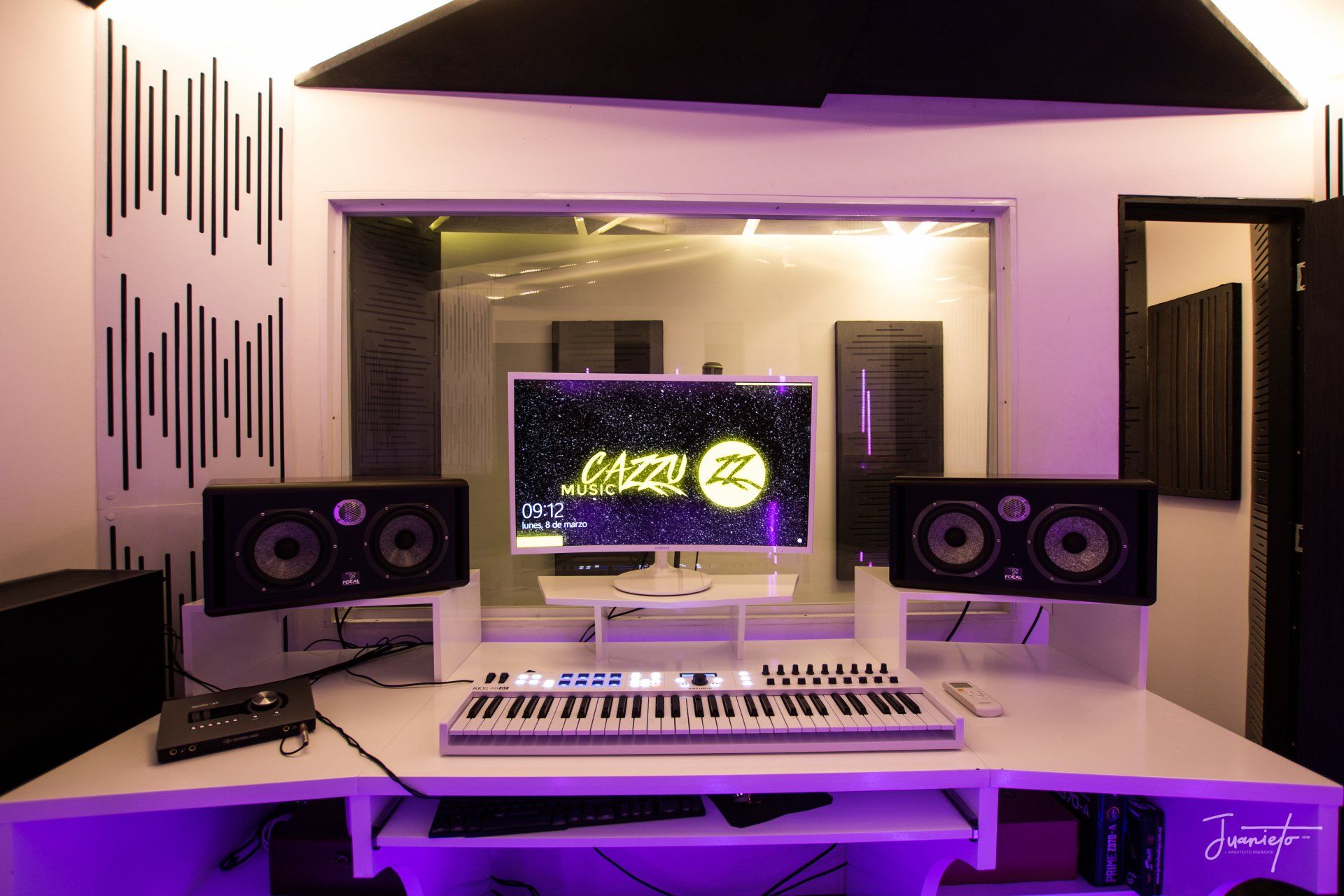 Un estudio de grabación con un teclado, un monitor y altavoces.