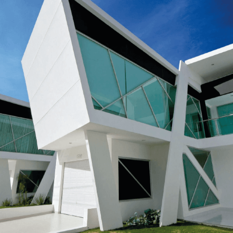 Un edificio blanco con ventanas verdes y un cielo azul al fondo.