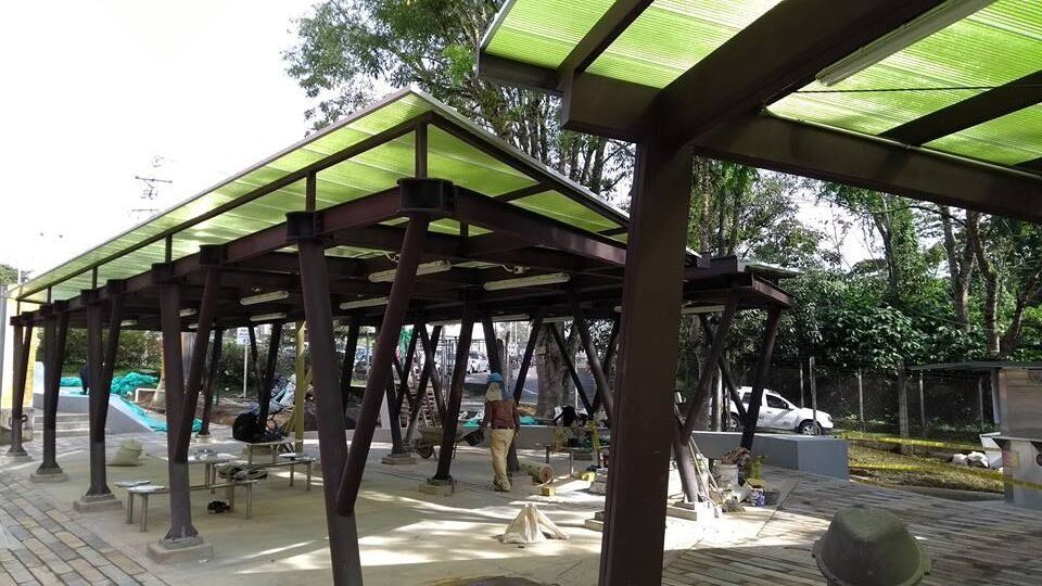 Una estructura de madera con techo verde en un parque.