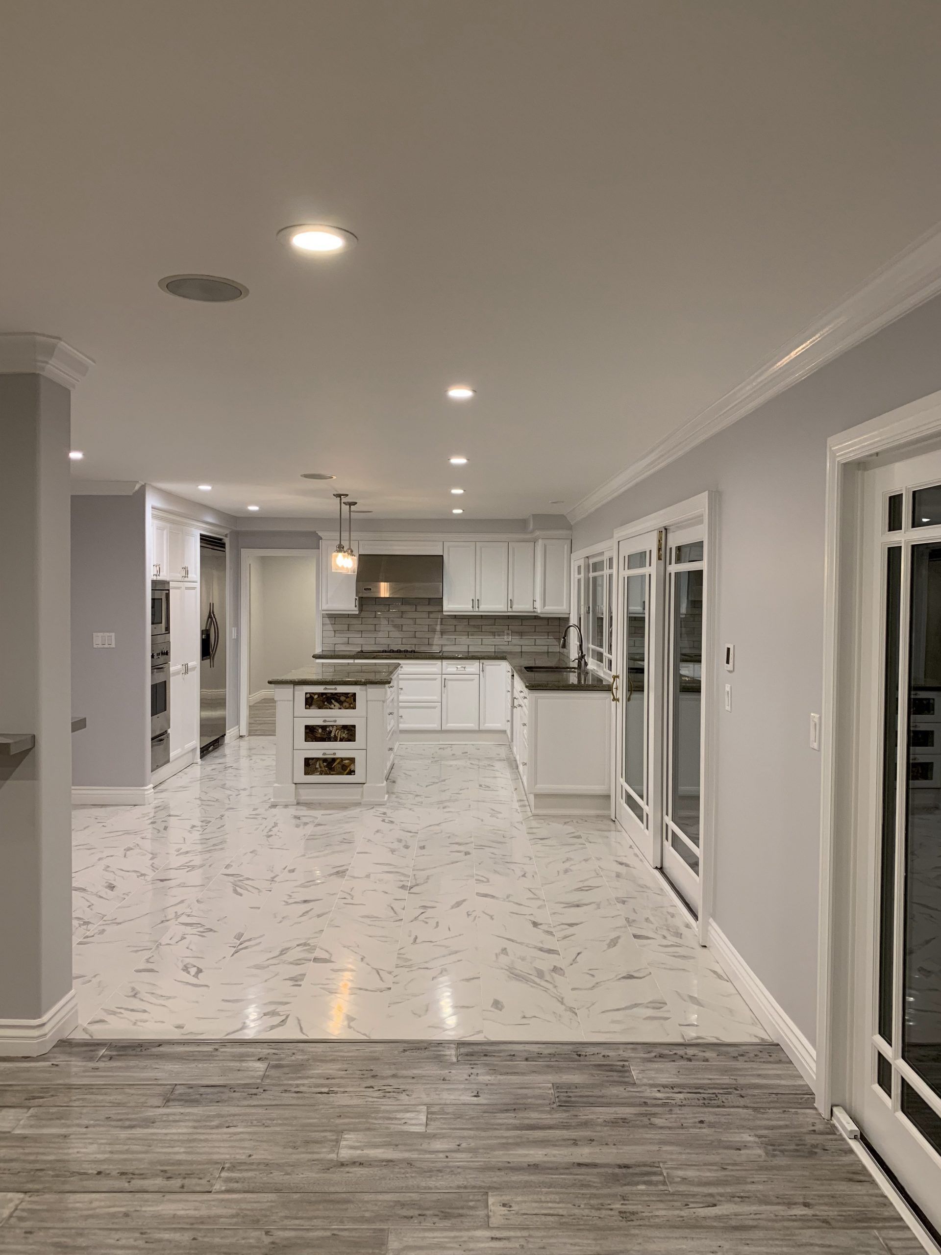 Spacious kitchen with white cabinets, island, and patterned tile floor; sliding glass doors.