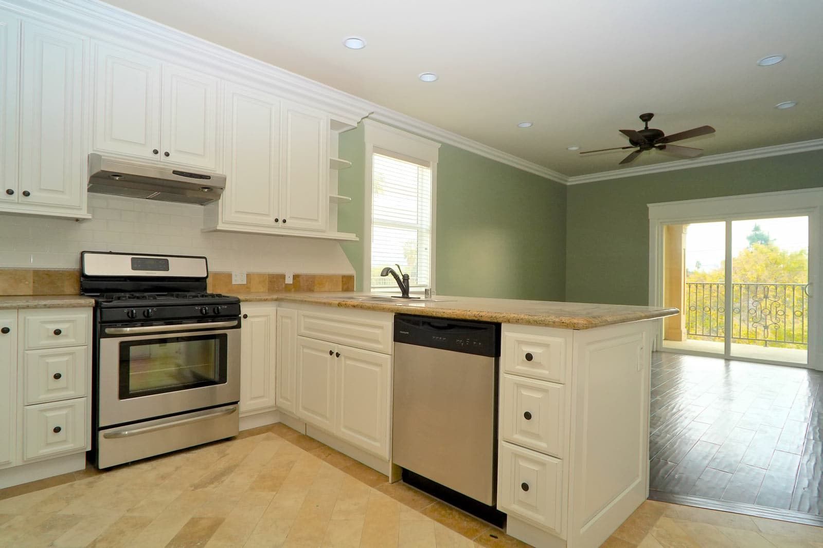 White kitchen with stainless steel appliances, granite countertops, and a view.