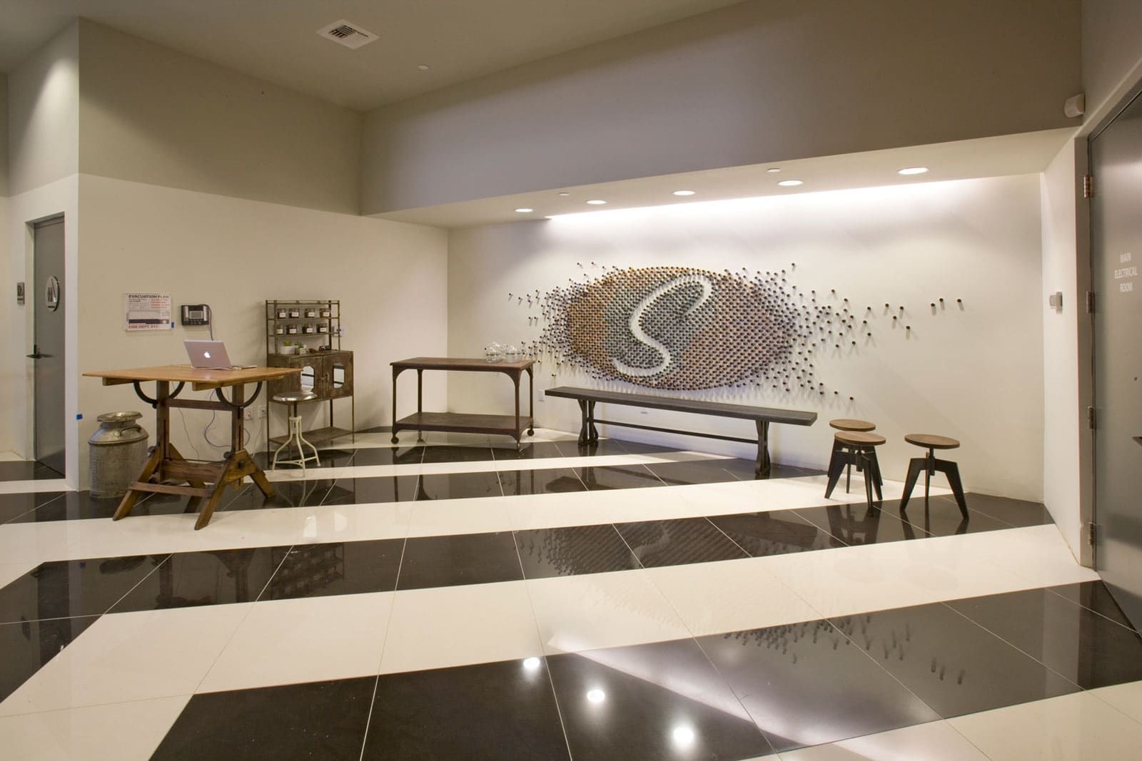 Lobby with black and white floor, wooden furniture, artwork on the wall.