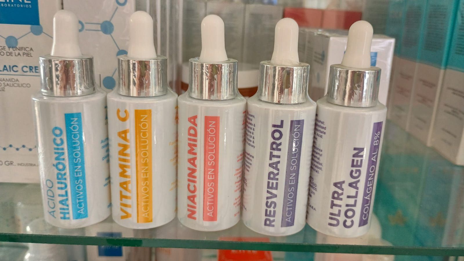 Cinco frascos de vidrio con gotero que contienen sueros para el cuidado de la piel