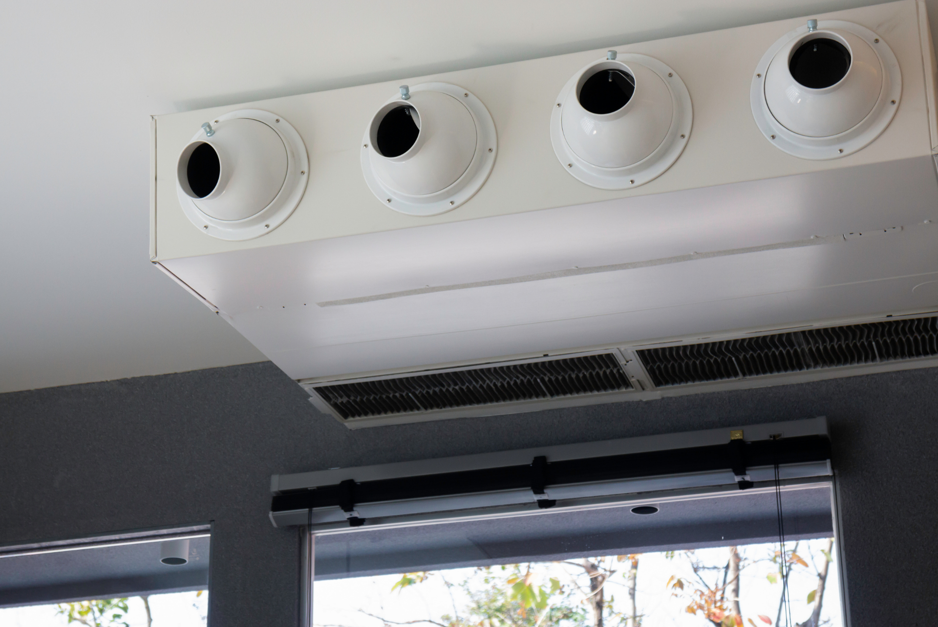 A white air conditioner is hanging from the ceiling in a room.