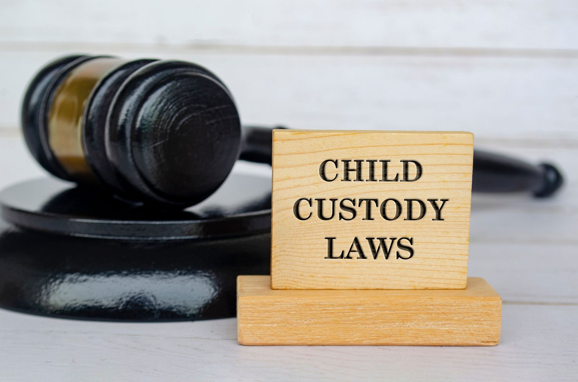 Wooden blocks engraved with Child Custody Laws text beside a gavel representing legal family matters. Wooden blocks engraved with Child Custody Laws text beside a gavel representing legal family matters.