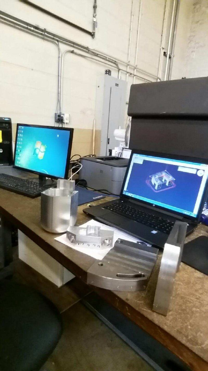 A laptop computer is sitting on a desk next to two monitors.