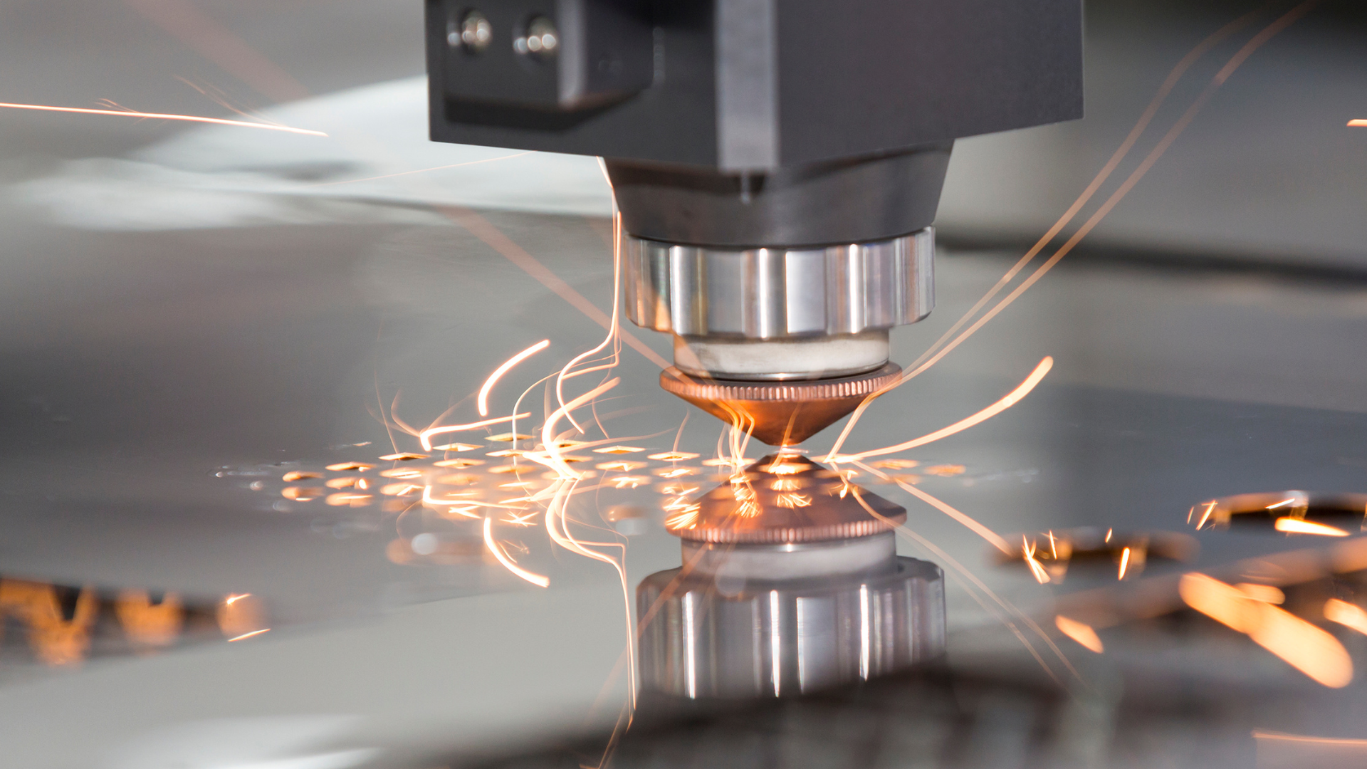 A machine is cutting a piece of metal with sparks coming out of it.