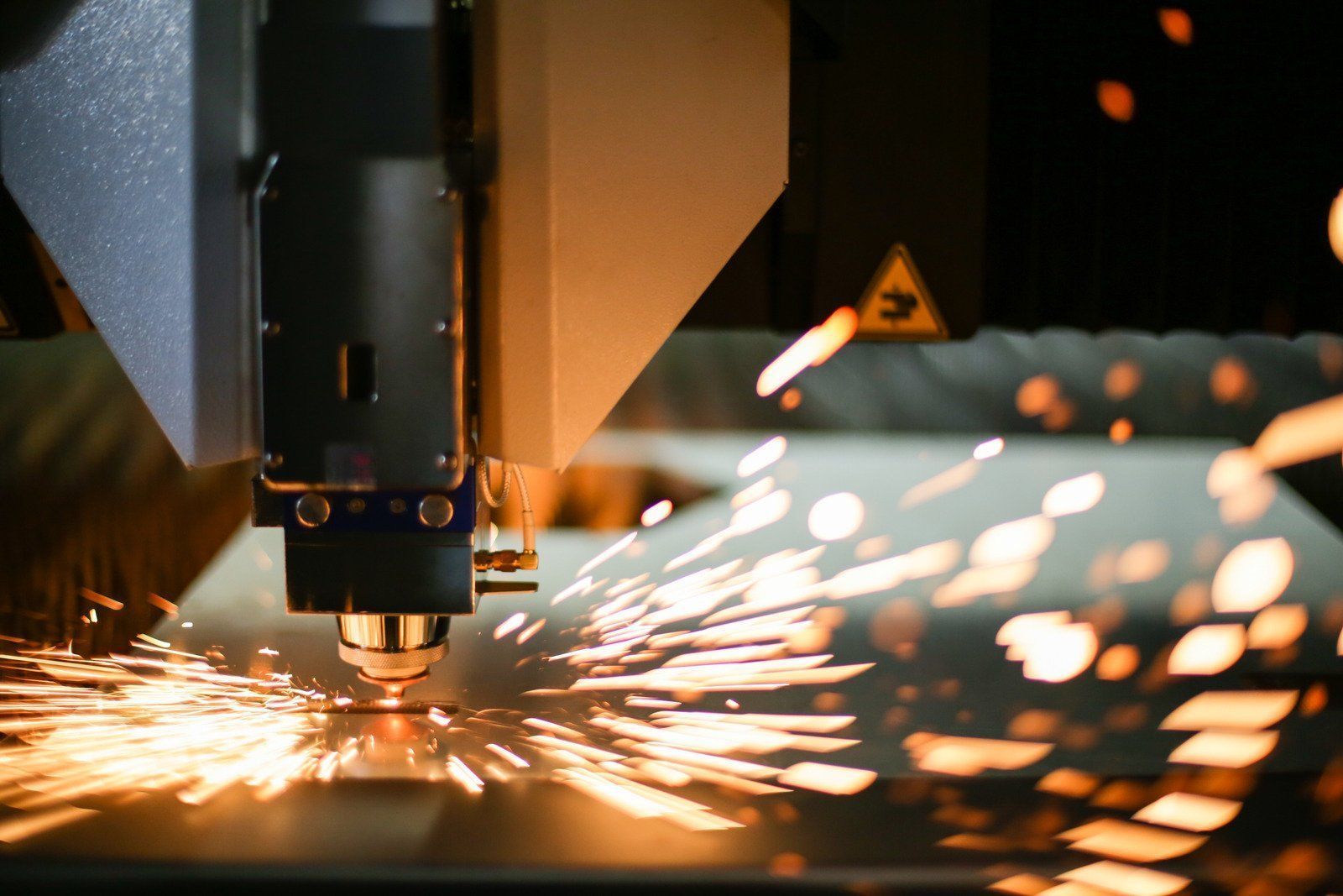 A machine is cutting a piece of metal with sparks coming out of it.