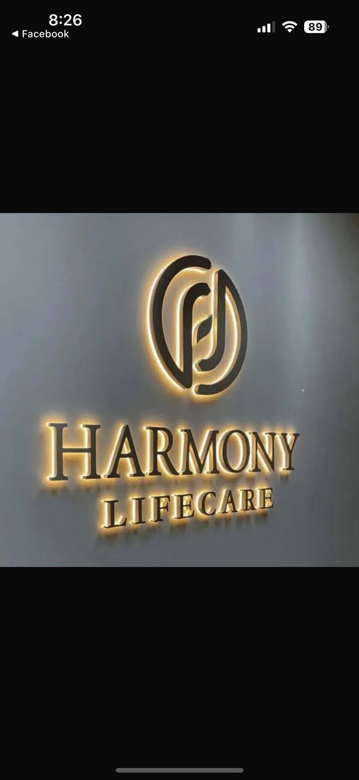 El logotipo de Harmony Lifecare está iluminado en una pared.