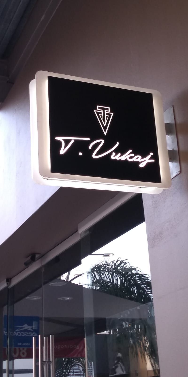 Un cartel de T. Vikaf cuelga sobre una puerta de cristal.