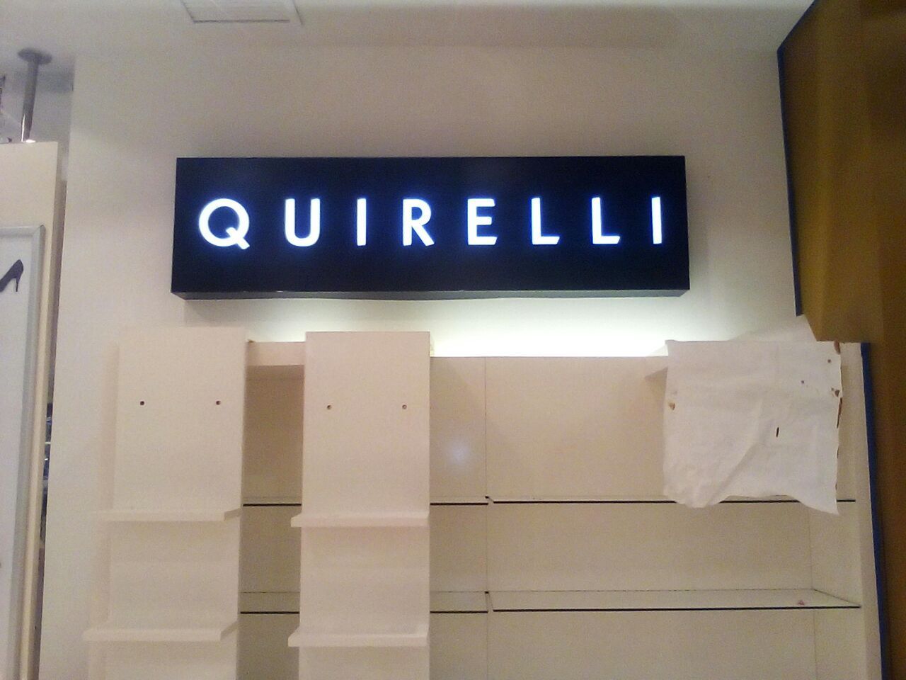 Un cartel de Quirelli está iluminado en una tienda.