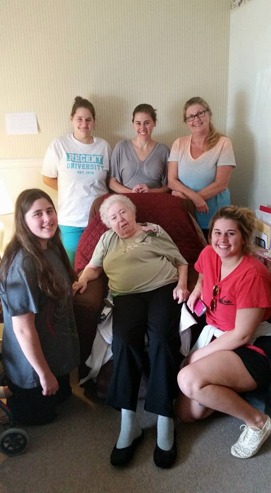 old woman surrounded by young care givers