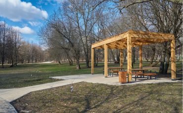 A photo taken at San Bernardino National Forest. In the photo you can see a pergola with park benches sitting underneath it.