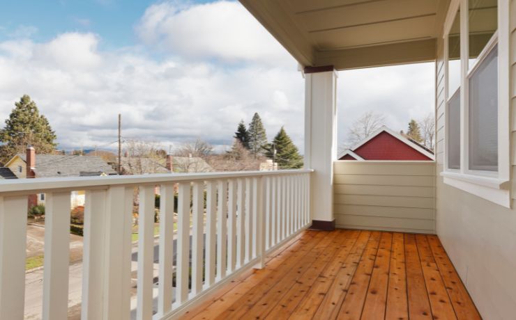 A photo of a beautiful small porch in San Bernardino, California. The porch has wooden floors and white railings. The porch is protected from the elements with a solid and sturdy roof.