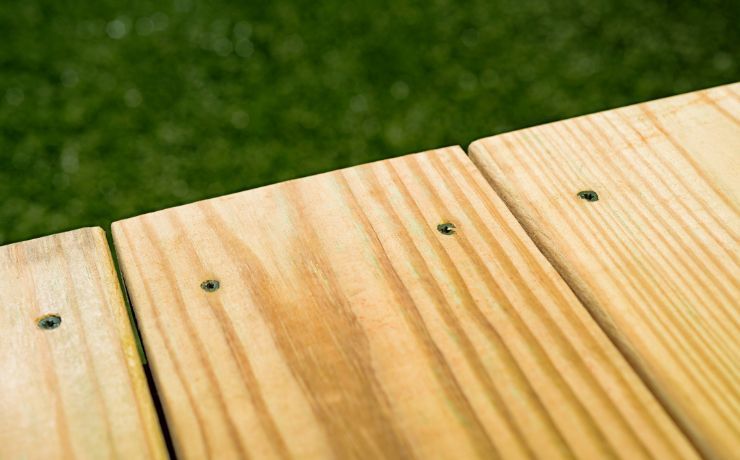 An up-close photo of a newly constructed deck. The photo shows the use of pressure-treated wood on the deck.