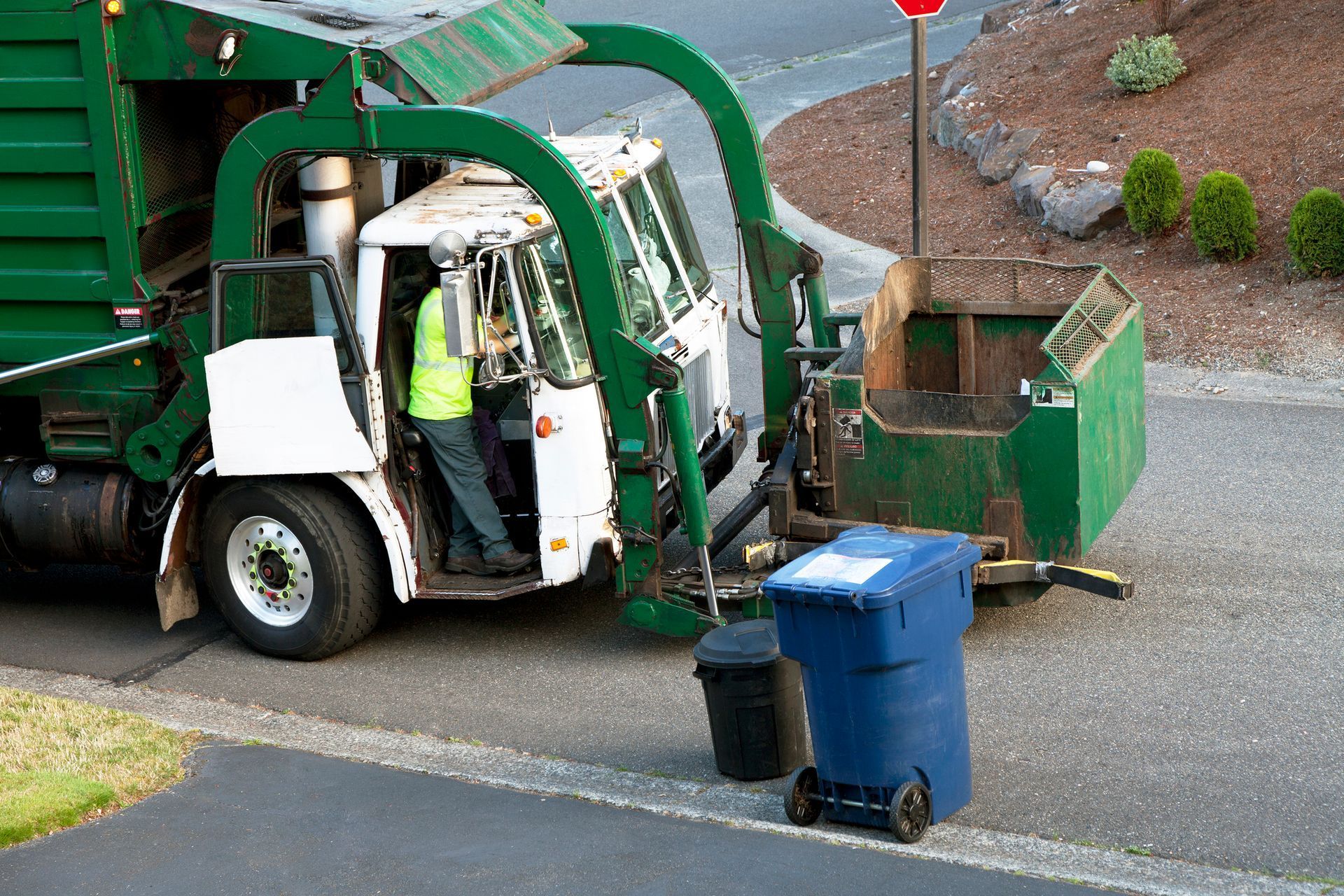 A garbage truck is parked on the side of the road.