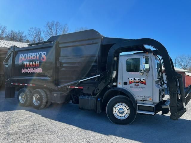 A bobby 's trash truck is parked on the side of the road