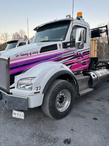 A blue dumpster filled with lots of junk is parked on the side of the road.