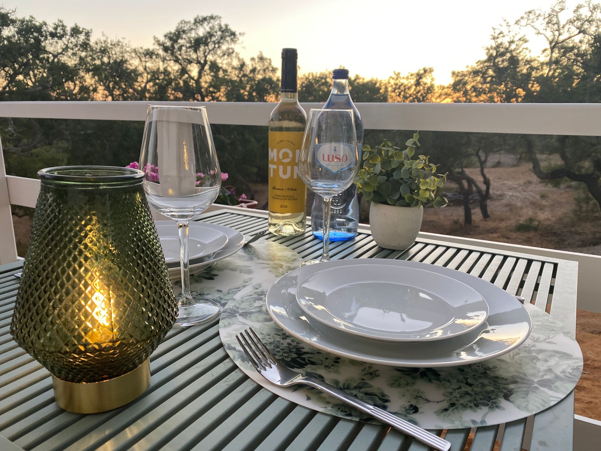 A table with plates glasses and a bottle of wine on it